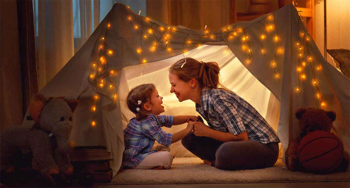 mother and son smiling in a play tent inside the house
