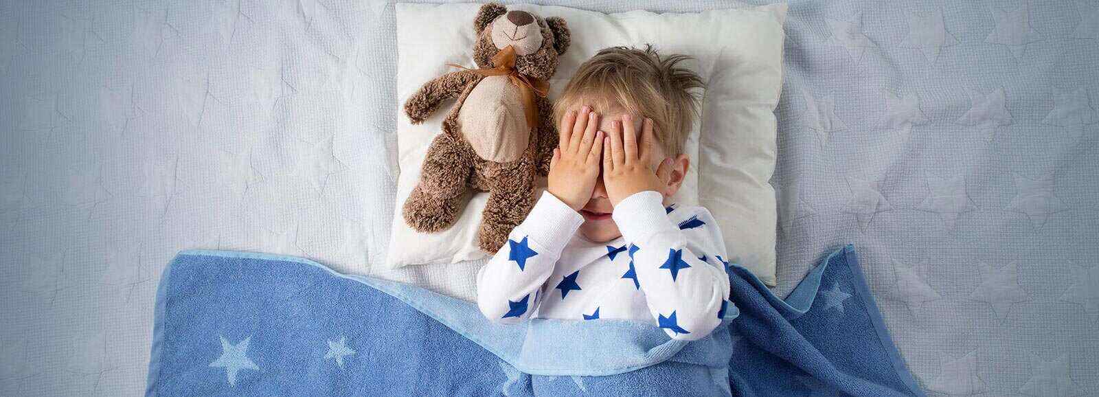 little boy in bed with a teddy bear