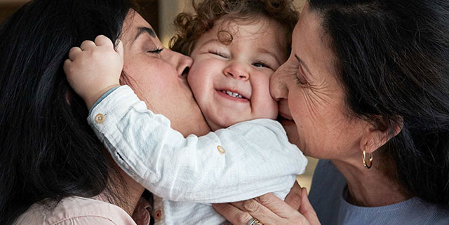 a mother and grandmother kissing a child